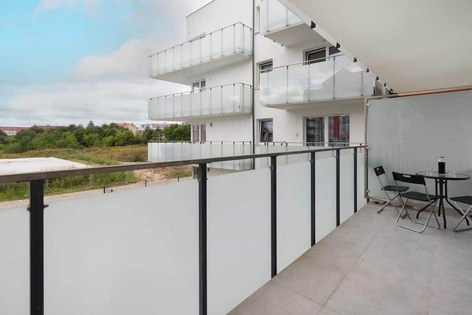 A spacious balcony with a glass railing, providing a relaxing outdoor area and a view of the green surroundings.

