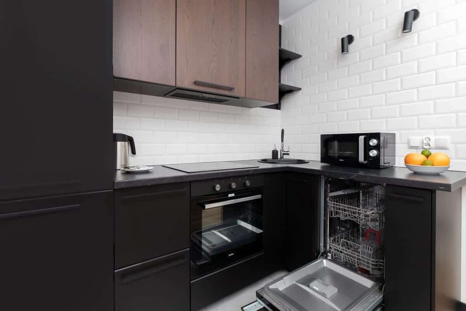 Another perspective of the kitchen, showing an open dishwasher and black countertops for a functional, modern design.

