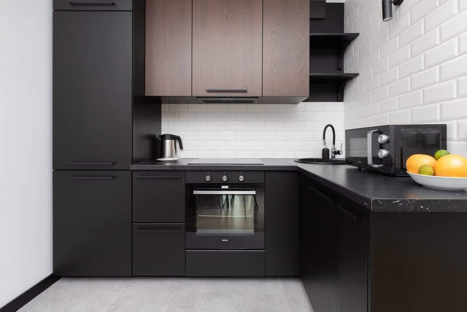 A sleek kitchen with dark cabinets, a tiled backsplash, and modern appliances, blending style and functionality.

