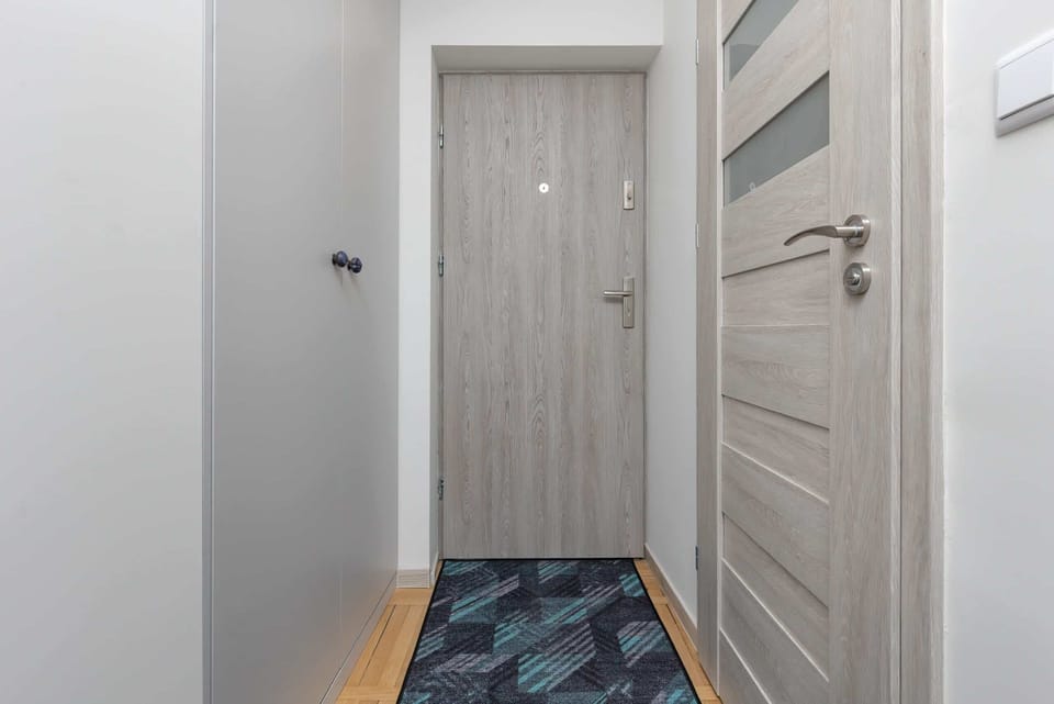 A hallway with white doors and a minimalist design, leading to the apartment’s main living areas.

