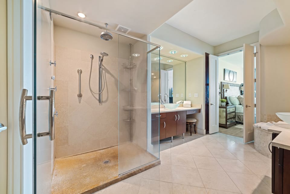 Modern bathroom showcasing a glass shower, vessel sink, and ample counter space, designed for both beauty and practicality.