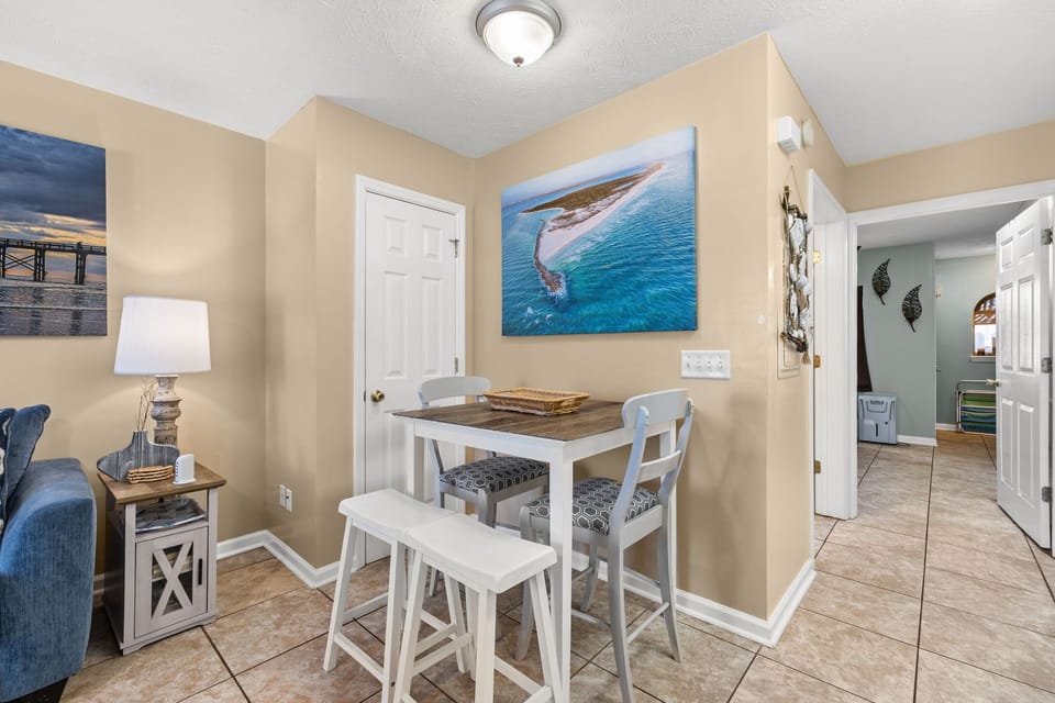 Cozy dining area with coastal artwork and natural lighting.