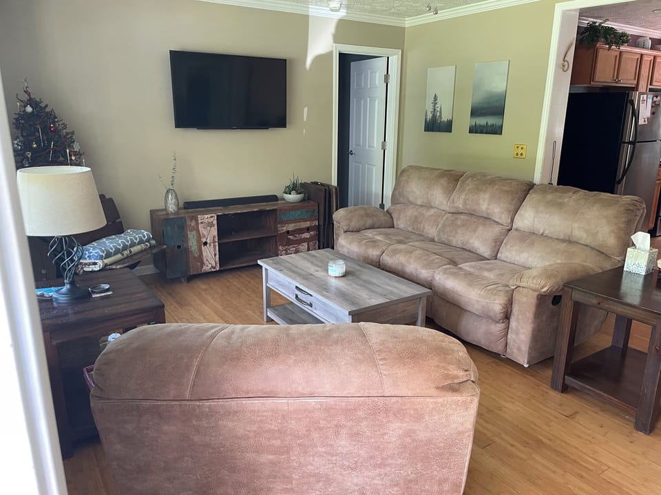 Living room w/ smart TV, recliner chair and dual recliner couch. 