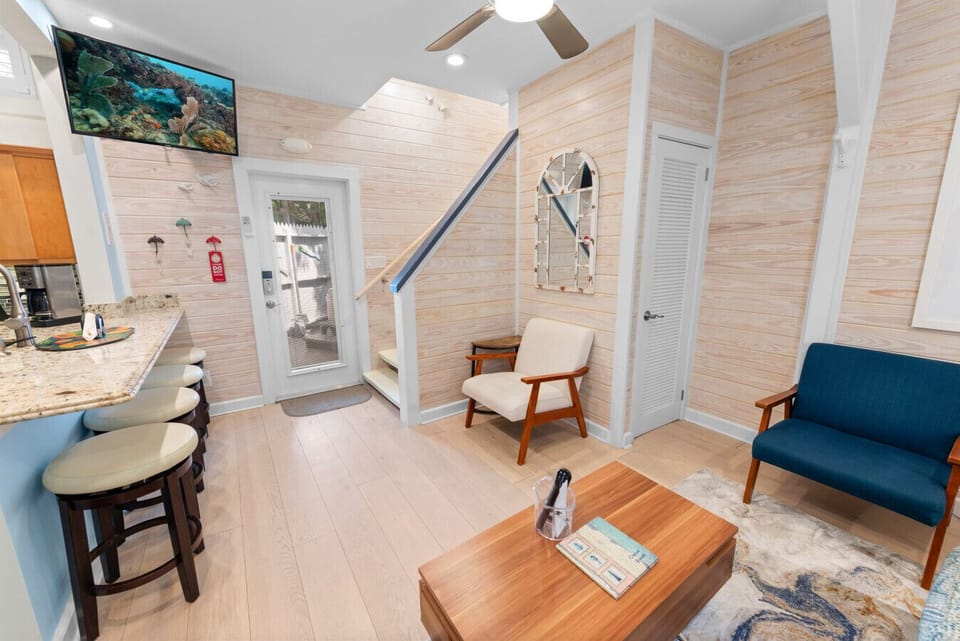 White louvered door has a cordless Dyson vacuum, iron/ironing board, stool.