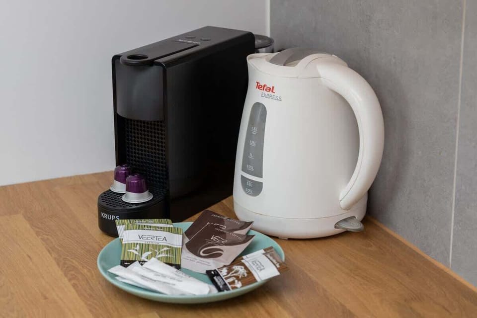 A coffee and tea station equipped with a coffee maker, kettle, and complimentary drinks.

