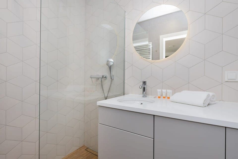 A sleek and clean bathroom with a floating vanity and a round mirror.

