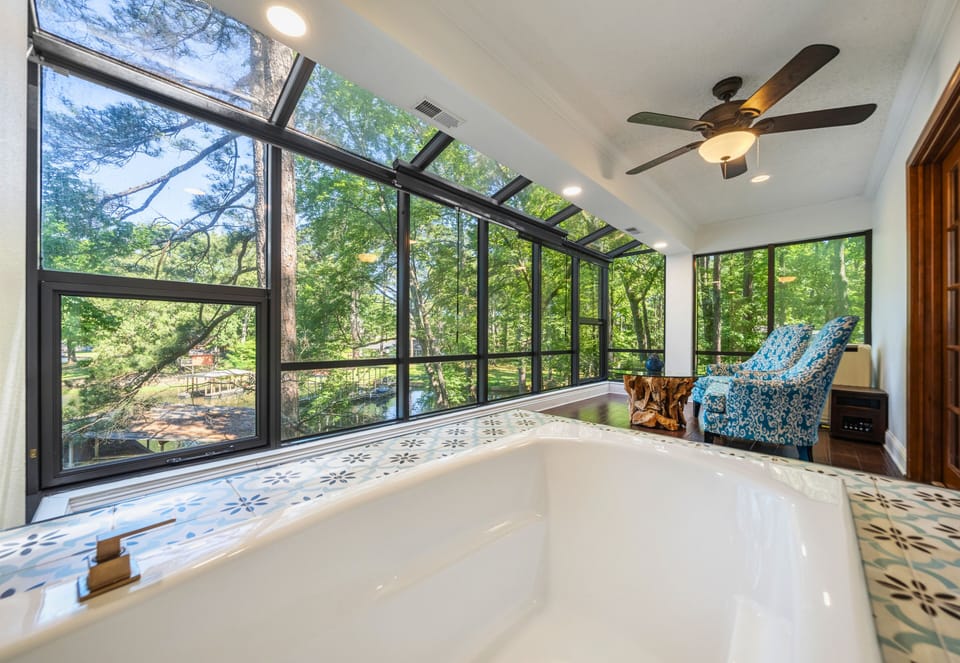 The soaking tub surrounded by windows offers a spa-like experience with peaceful nature views in every direction.