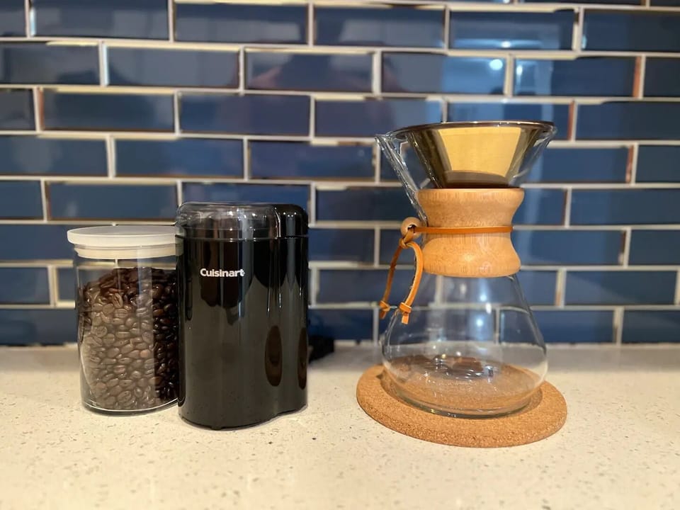A full coffee bar with chemex, drip coffee, coffee beans and a grinder.