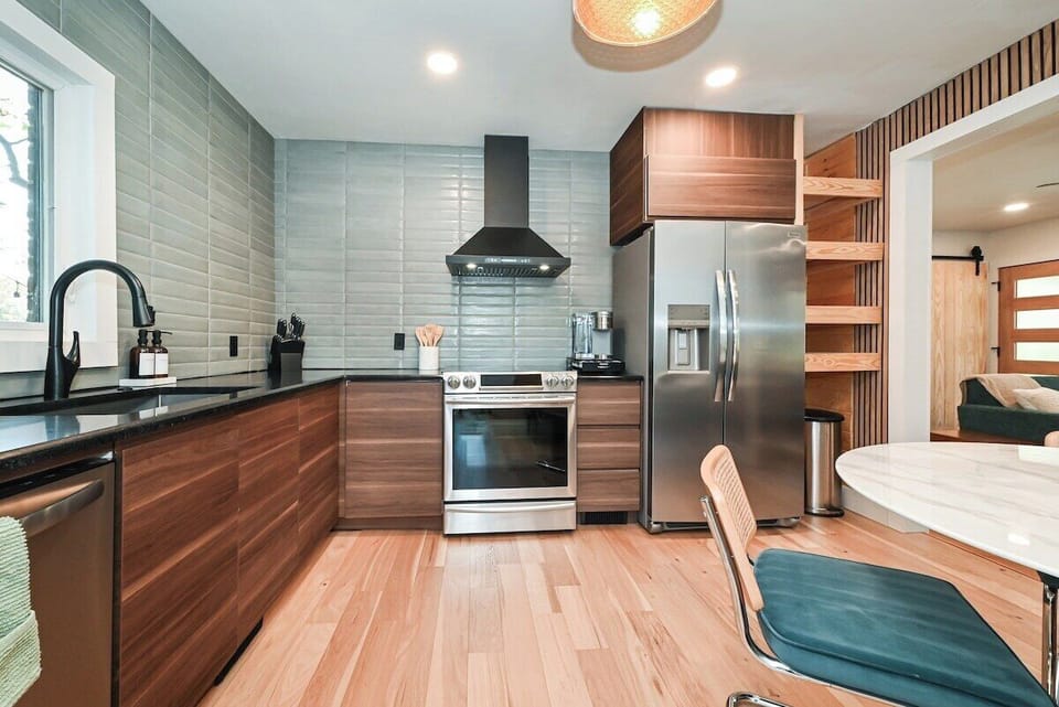 Fully equipped kitchen with premium stainless steel appliances, deep farmhouse sink, and sleek wood cabinetry.
