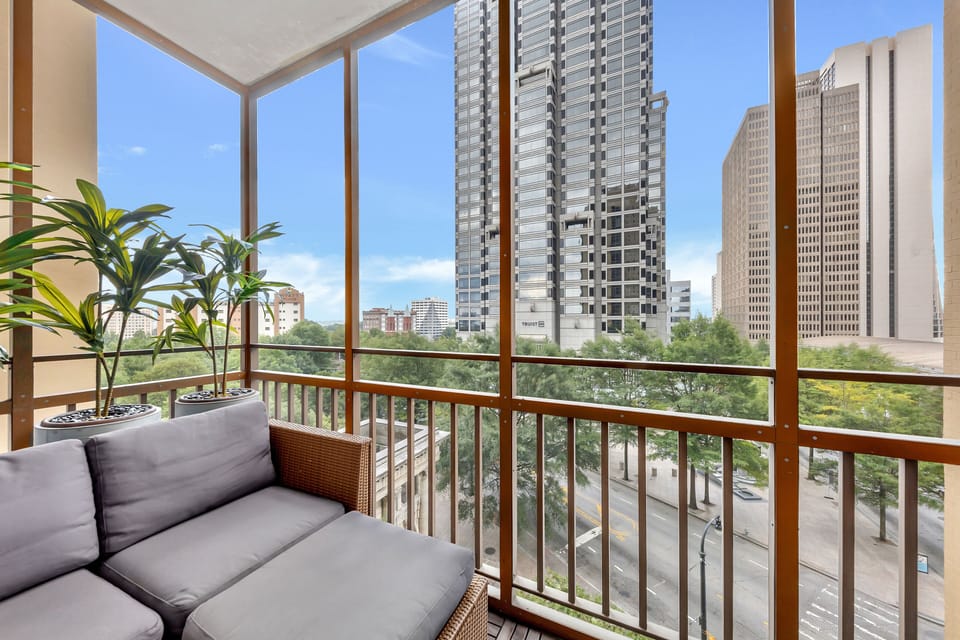 Screened balcony w/ cushioned seating & city skyline views