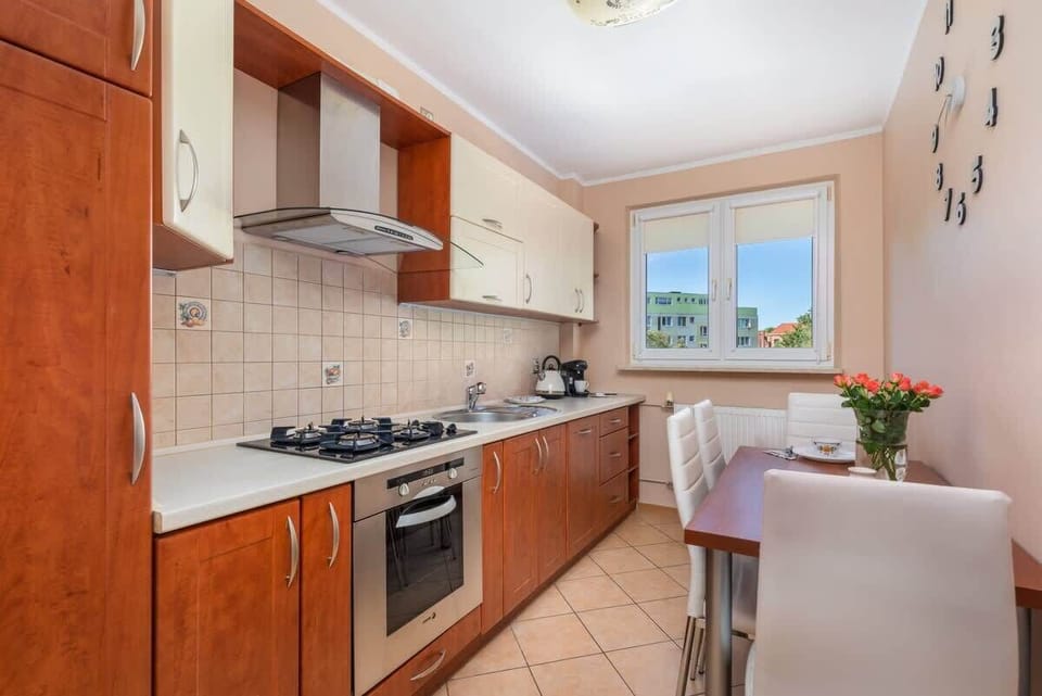 A traditional kitchen with wooden cabinets, tiled backsplash, and a small dining area, blending classic design and practicality.

