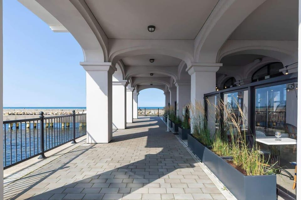 An arched walkway with railings overlooking the sea, providing a sheltered outdoor space with coastal vistas.

