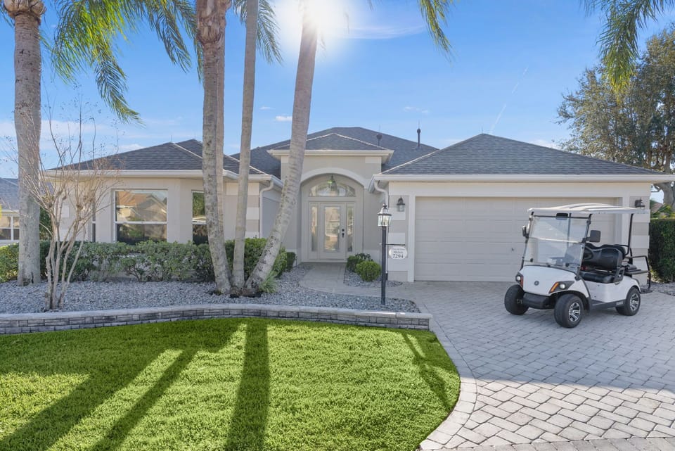Beautiful single-story property with elegant architecture, manicured landscaping, and convenient golf cart access in a palm tree-lined setting.