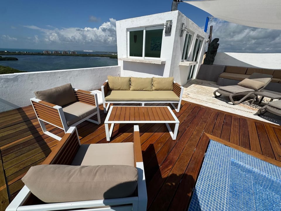 Private rooftop terrace with teak wood decking, cushioned seating, lounge chairs, and a tiled plunge pool.