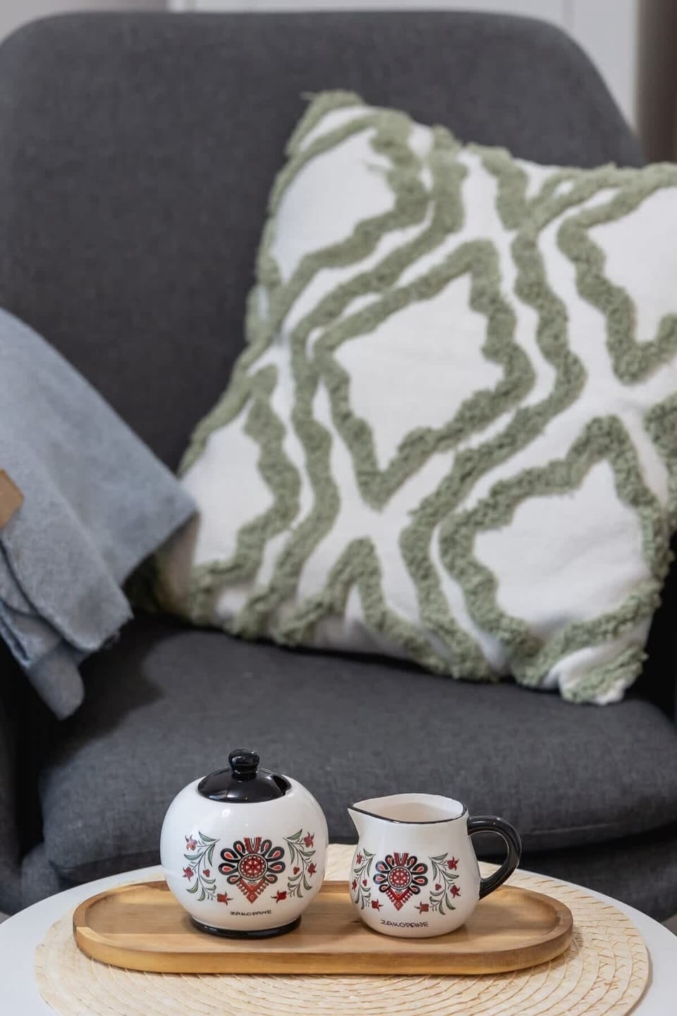 A close-up of a cozy seating area with a decorative pillow and a tray of coffee and snacks, perfect for relaxation.
