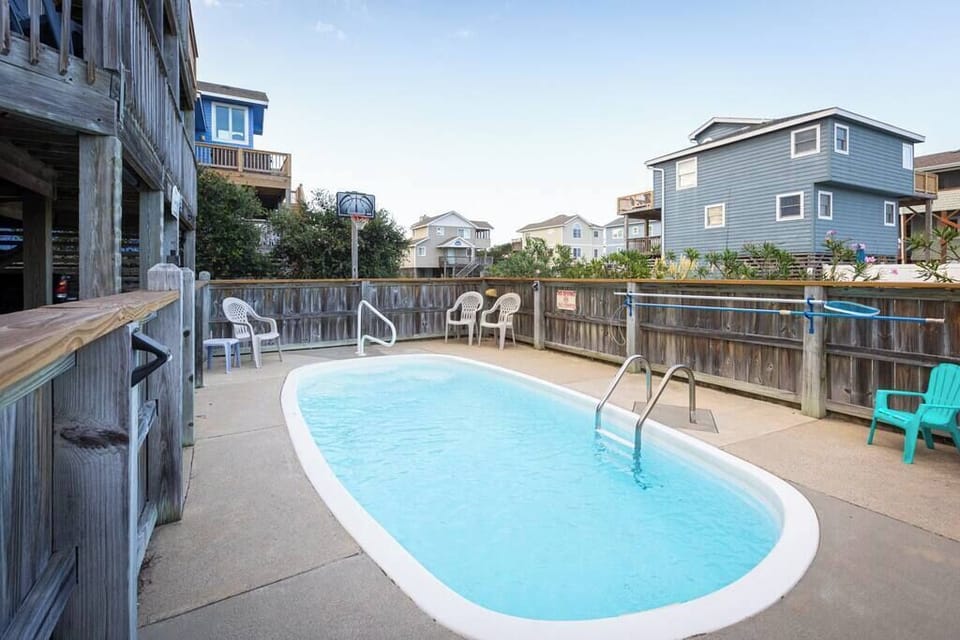 Fully fenced private pool (non-heated) featuring a basketball hoop and poolside seating