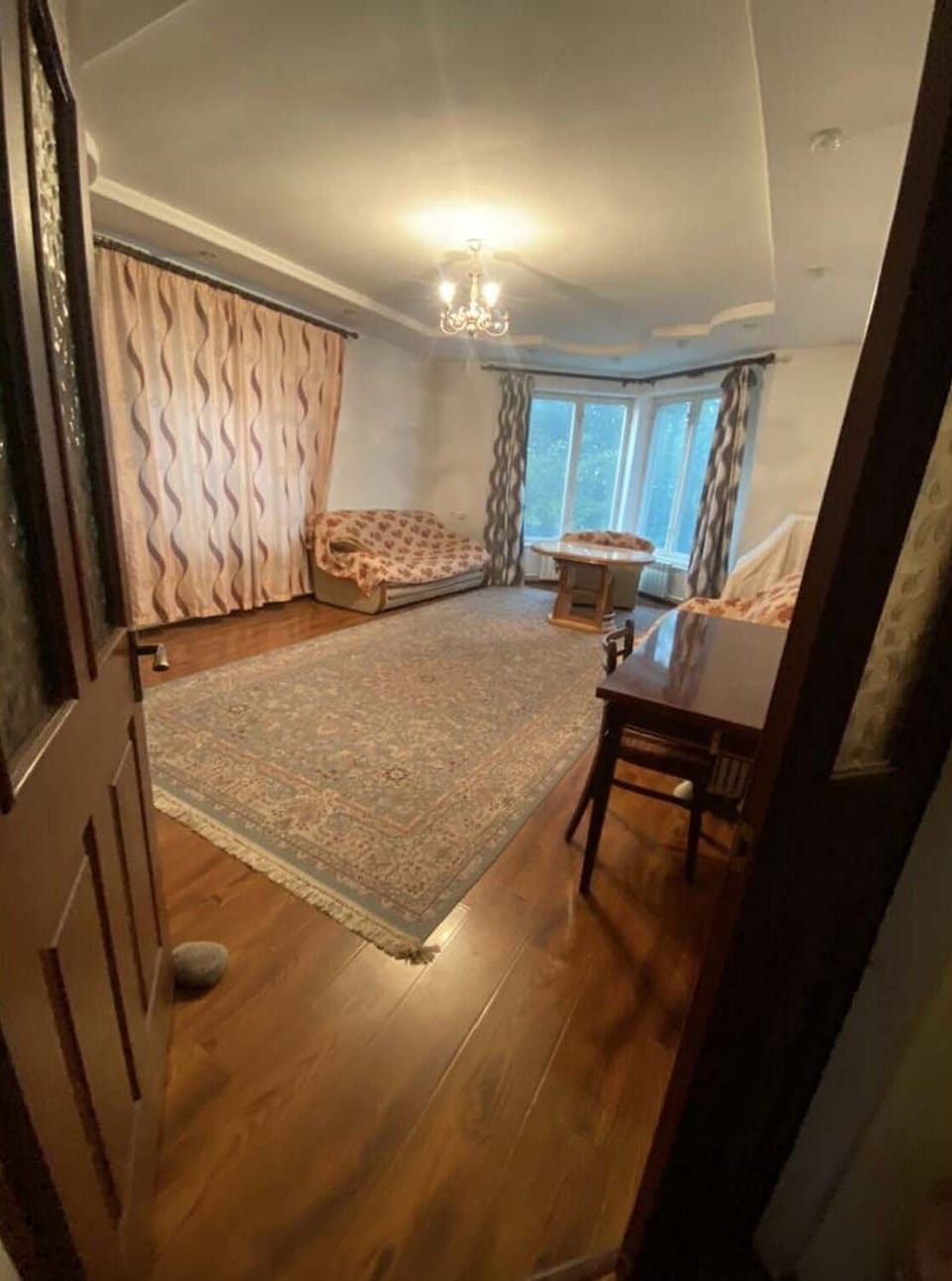 Large living room with comfy sofa, arm chairs, a table and a piano (surprise!)