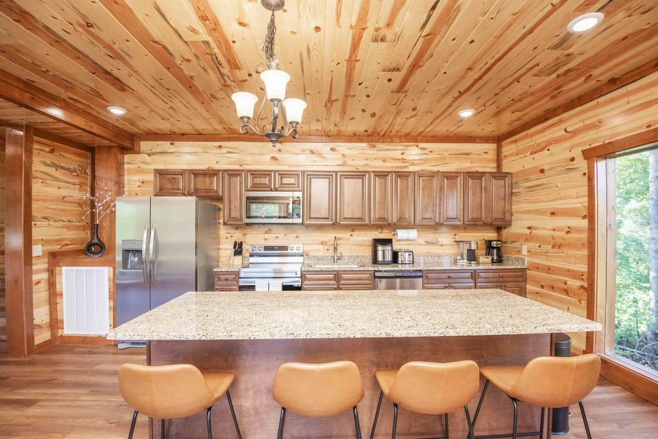 Large chef's kitchen featuring full size appliances, granite counter tops, and kitchen island with bar seating
