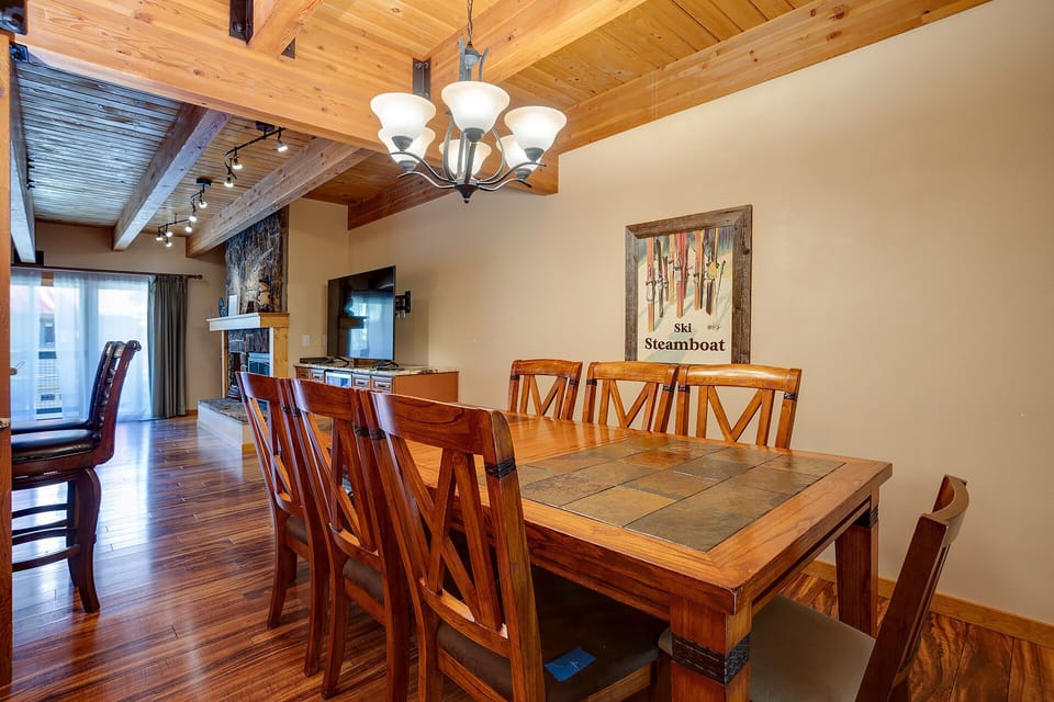 Gather around this rustic dining table where warm wood beams and charming ski decor create the perfect mountain retreat atmosphere.