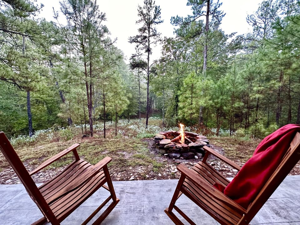 Hilltop patio has rocking chairs and a fire pit overlooking the pond below.