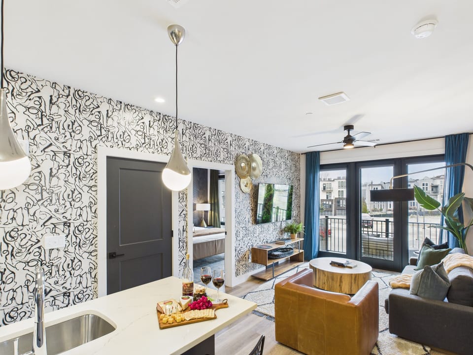 Open concept living area with smart TV, comfortable seating, designer decor, natural lighting, and access to private patio.