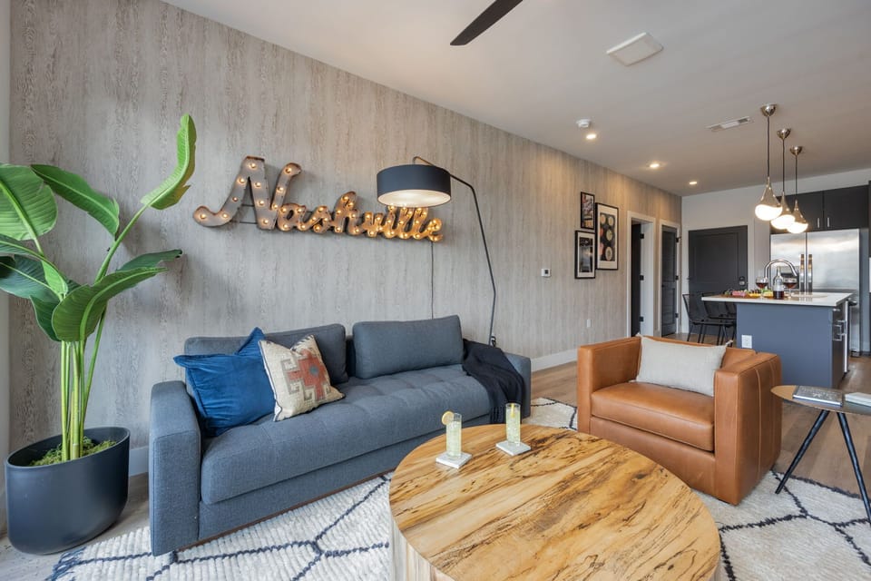 Open concept living area with smart TV, comfortable seating, designer decor, natural lighting, and access to private patio.