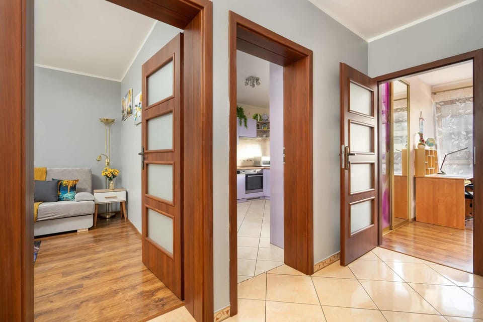A hallway with wooden doors and light tiles, leading to different rooms in the home with an open and welcoming feel.