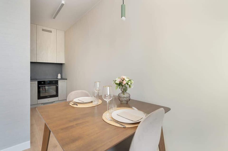 A compact dining area with a wooden table and chairs, accented by minimalistic decor and natural light.
