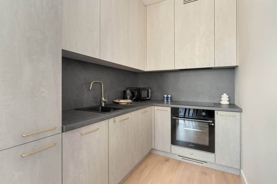 A sleek modern kitchen with gray cabinetry, a black countertop, and built-in appliances, designed for both style and functionality.
