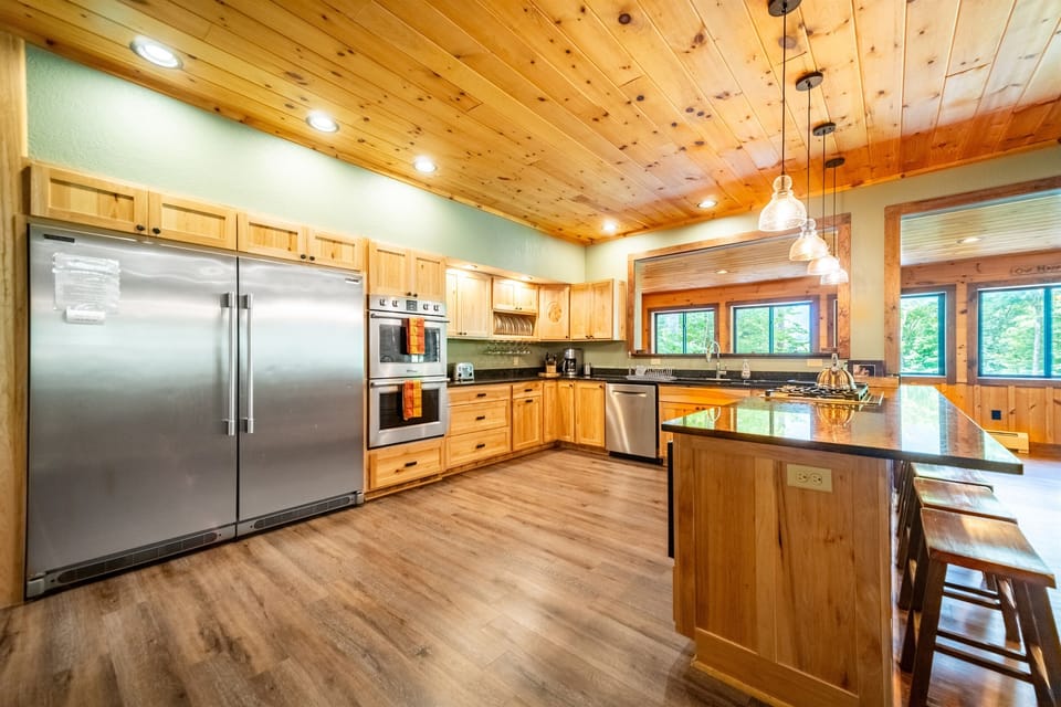 Boasting a range of appliances: a gas stove, commercial fridge, double ovens, a spacious kitchen island, all complemented by scenic mountain views.