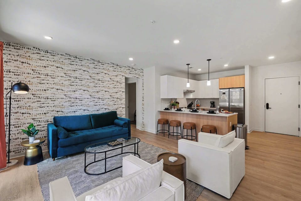 Bright open living space featuring smart flat-screen TV, designer furnishings, and patio entrance with pool view.