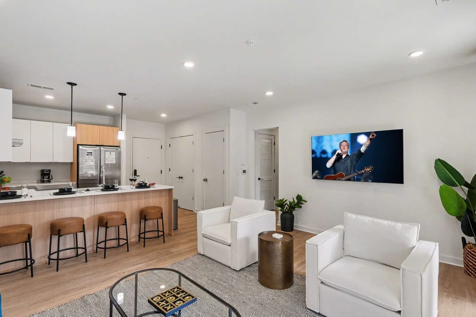 Bright open living space featuring smart flat-screen TV, designer furnishings, and patio entrance with pool view.