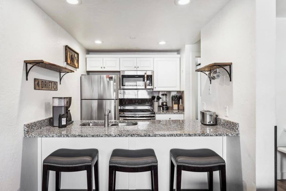 Kitchen bar: three bar stools, bridges the living room and kitchen, granite countertops, stainless-steel appliances, wide range of cookware