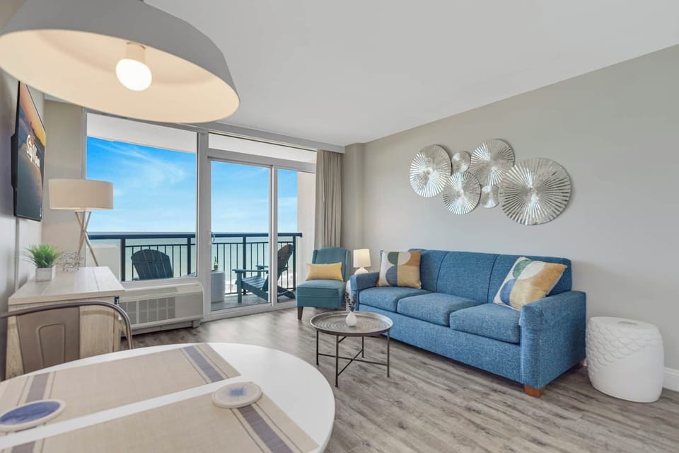 Relax with breathtaking ocean views from this bright, open living space—featuring a cozy sectional, beach-inspired décor, and a private balcony perfect for morning coffee or sunset wine by the sea.