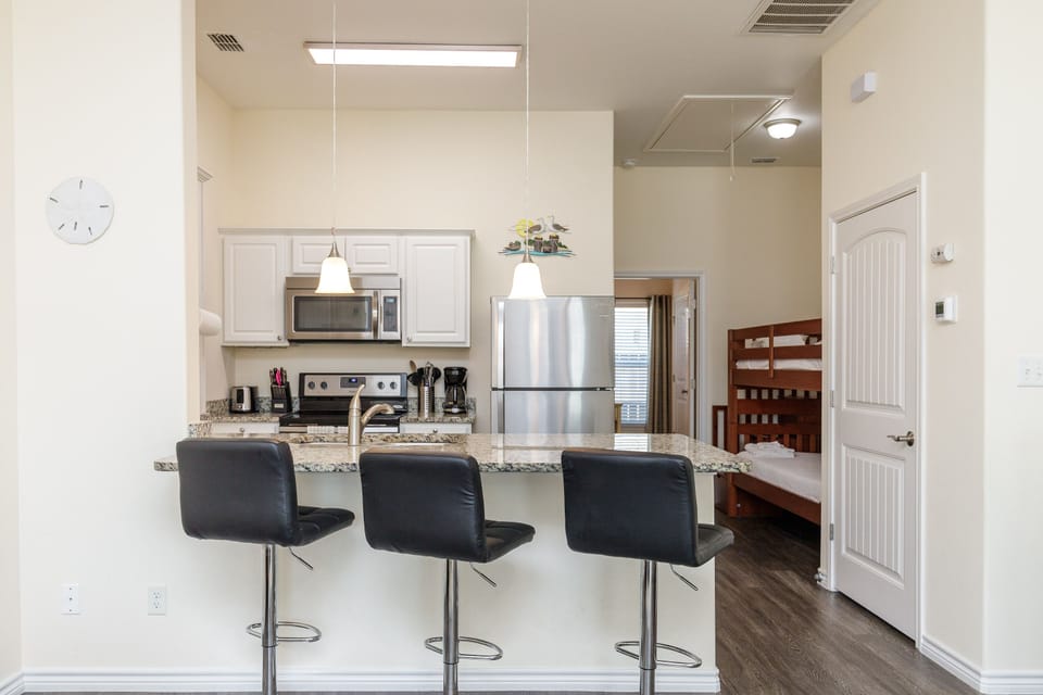 Your sleek modern kitchen features granite counters, stainless appliances, and a breakfast bar perfect for morning coffee or casual meals.