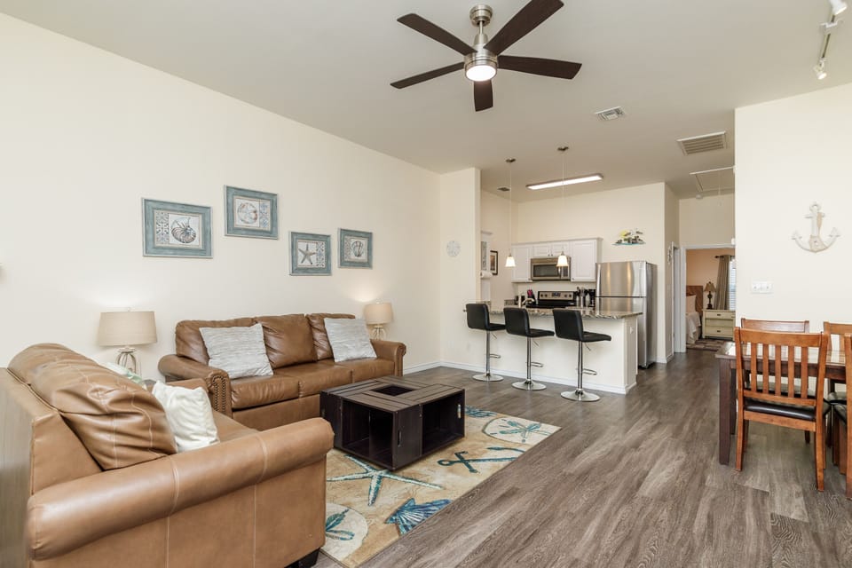 Sink into plush leather sofas while the ceiling fan keeps you cool in this open-concept space that flows seamlessly to your modern kitchen.