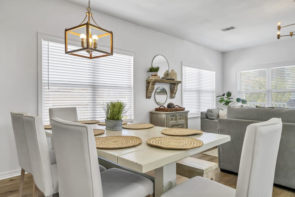 Past the kitchen area is an extra large dining table with 6 chairs and a long bench