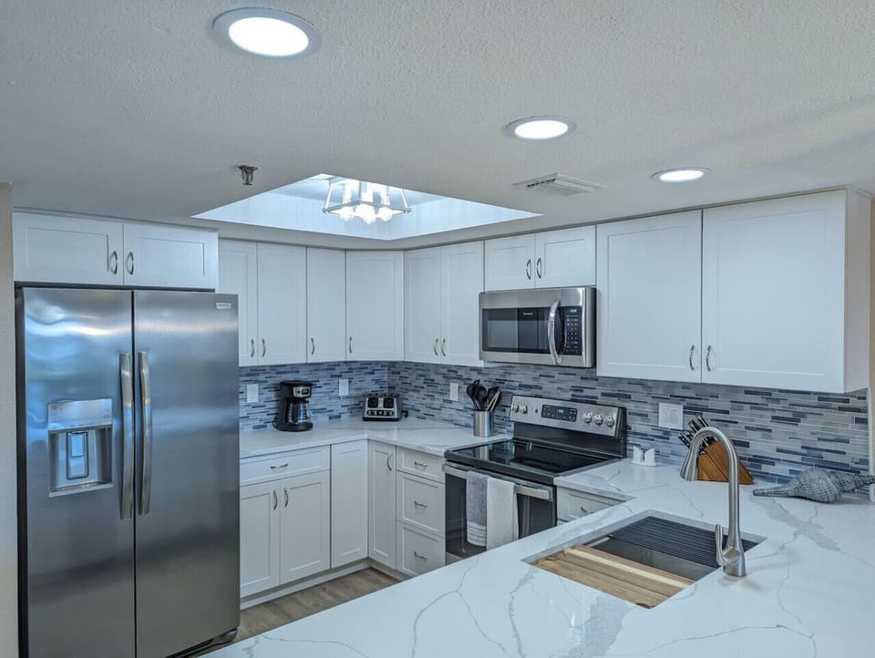 Modern kitchen w/ stainless appliances, ample counter space, & clean, bright finishes
