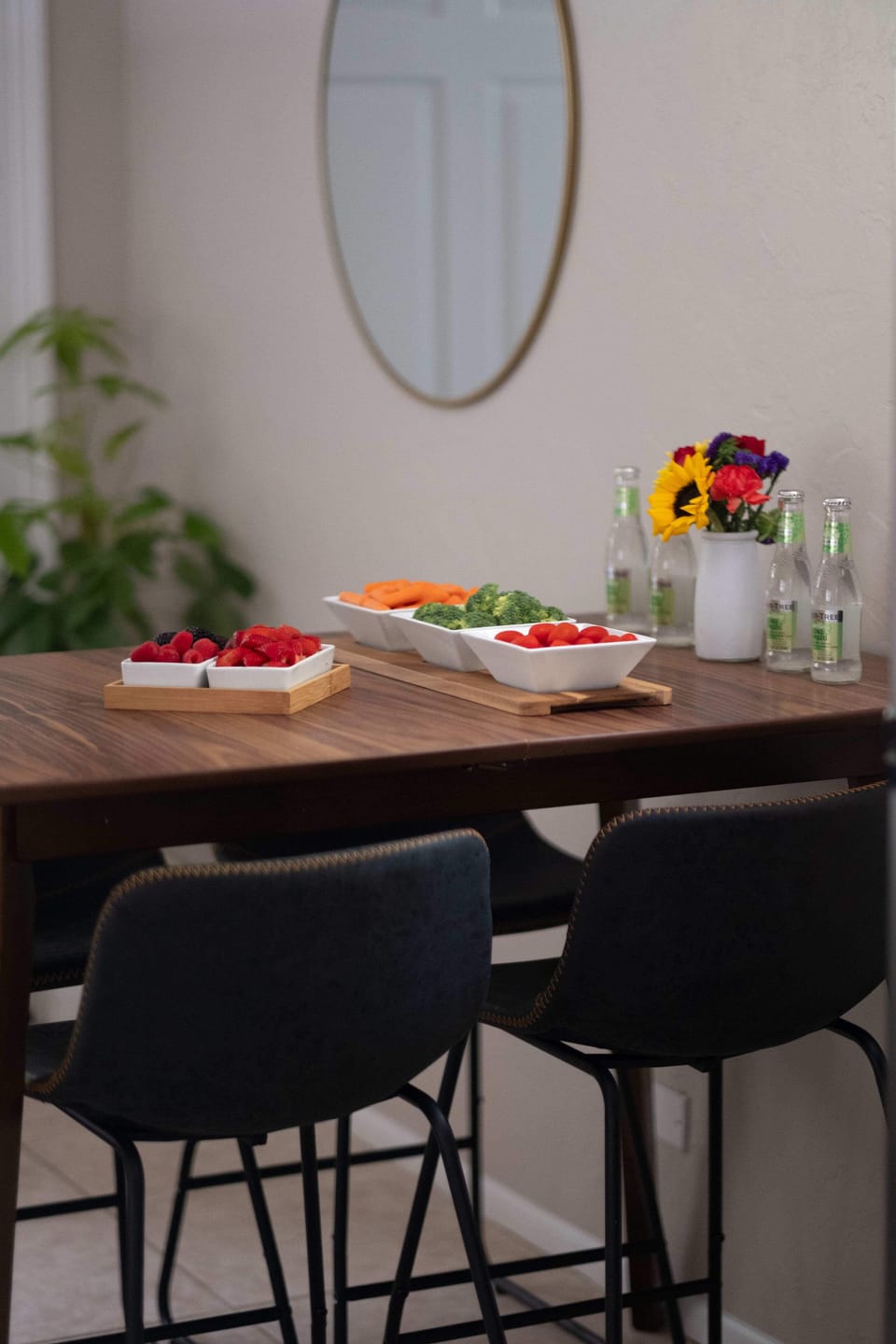 A sun-filled corner designed for relaxation. This inviting dining area features a beautiful wood-tone table, contemporary seating, and thoughtful touches like fresh greenery and a sleek statement mirror.