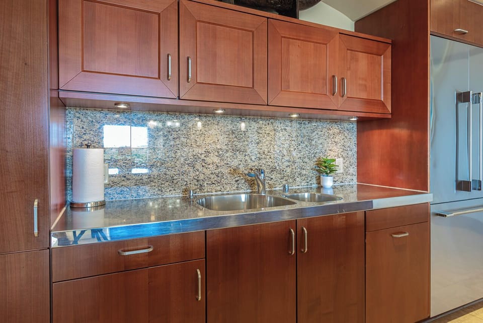 Your kitchen is ready for vacation cooking with warm wood cabinetry, granite countertops, stainless steel appliances, and a modern granite backsplash that catches the light beautifully.