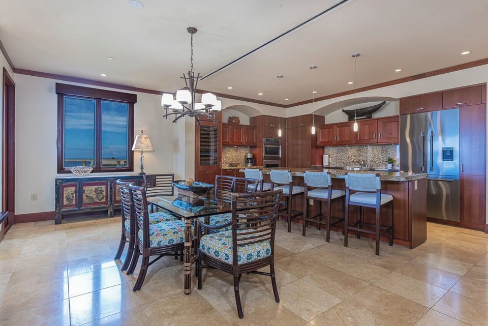 Your open-plan kitchen and dining area invites you to cook and gather together. Rich wood cabinetry, granite counters, stainless appliances, and ocean views through the windows create a warm, elegant space for memorable meals.