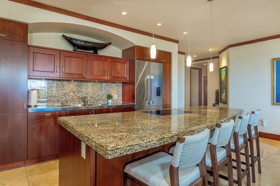 Gather around this spacious granite island, where rich wood cabinetry and modern amenities meet coastal charm. Five bar stools invite you to enjoy morning coffee or evening conversations in your perfectly equipped kitchen.