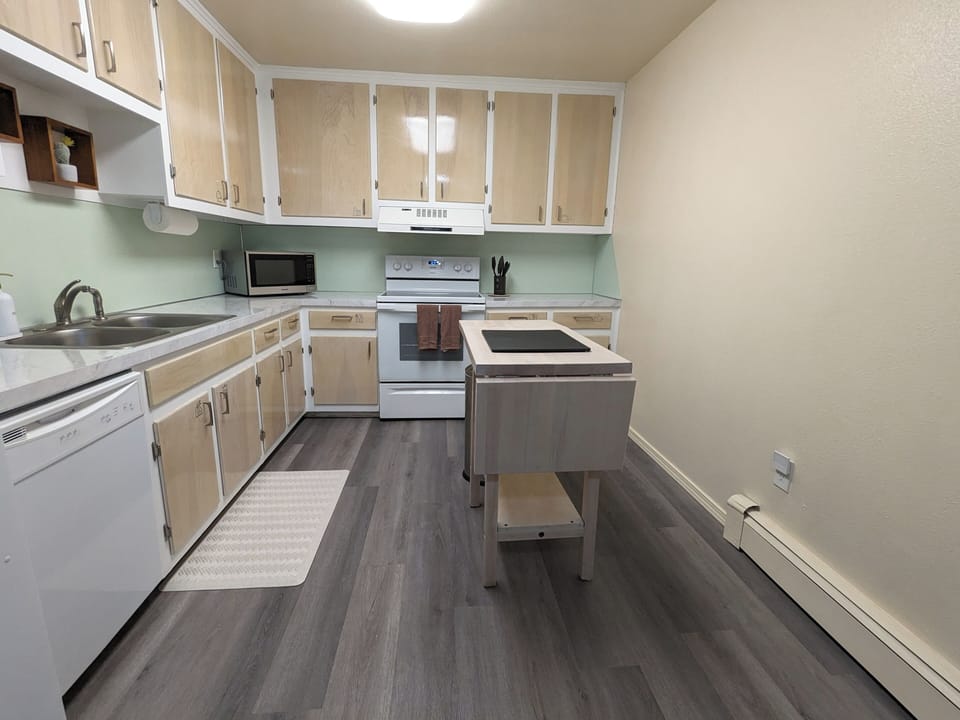 Bright kitchen with light appliances and a central kitchen island for pre space.