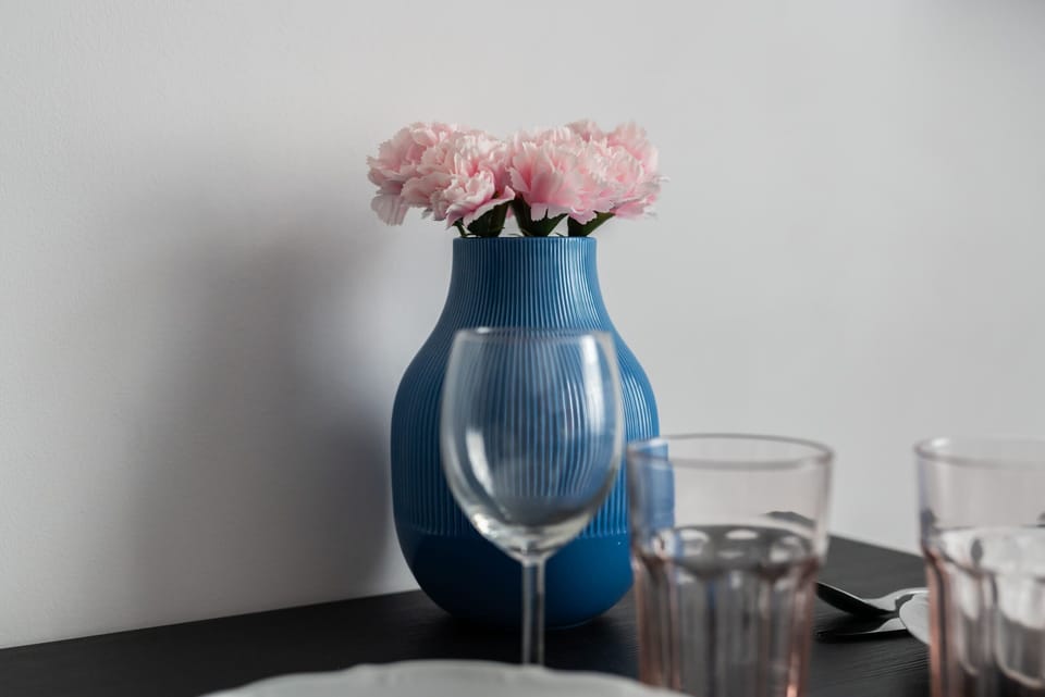 A close-up of a small vase with flowers and glasses, adding a charming decorative touch to the room.
