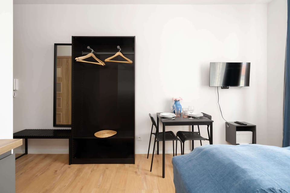 A wardrobe area with an open closet, hangers, and a small workspace, providing functional storage.
