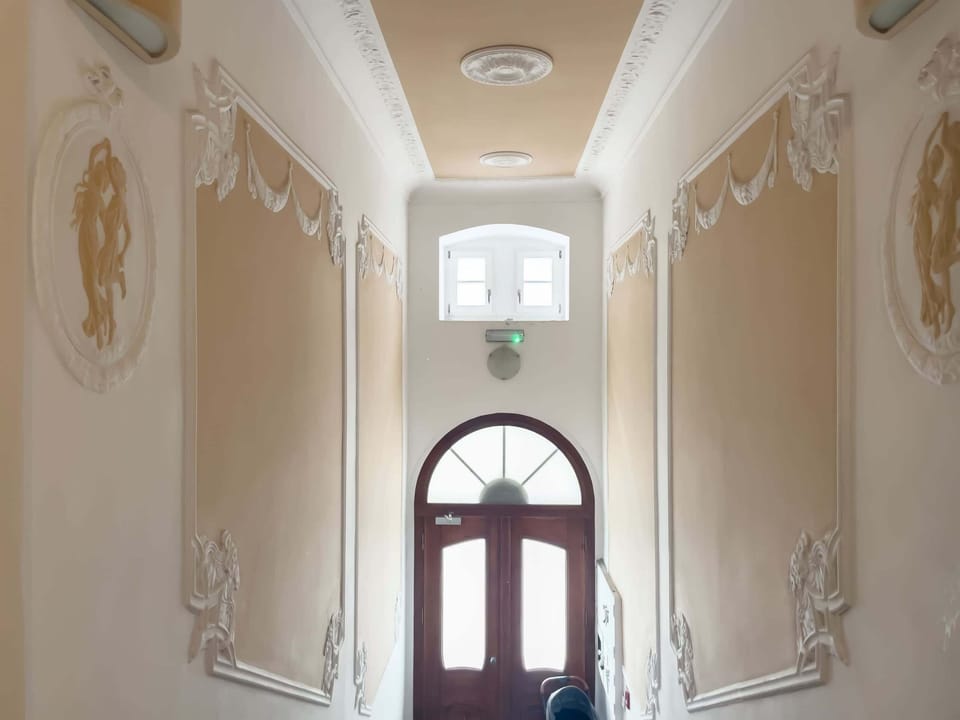 An ornate building entrance with decorative details and natural light pouring through, emphasizing its classic style.
