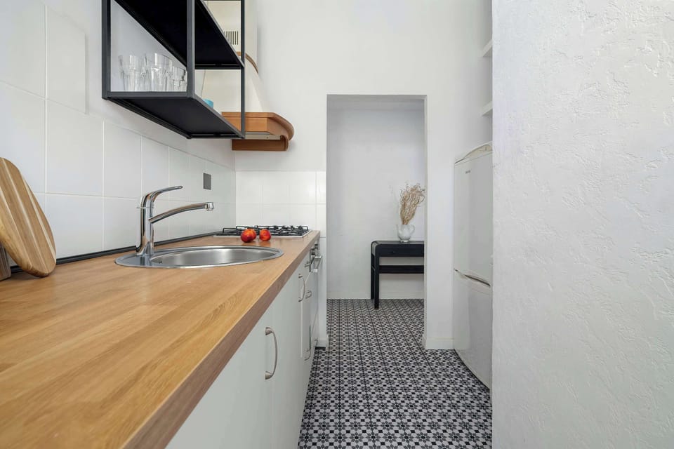 A kitchen perspective reveals long work surfaces with wood finishes and compact appliances. The narrow design uses space efficiently.
