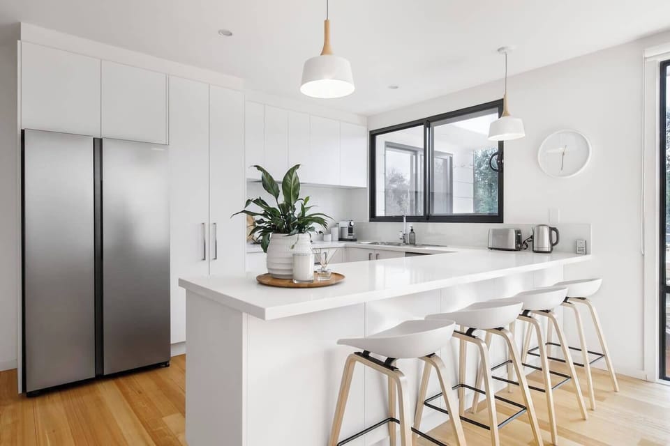 Bar top seating for four frames an all-white, contemporary and bright kitchen with premium appliances
