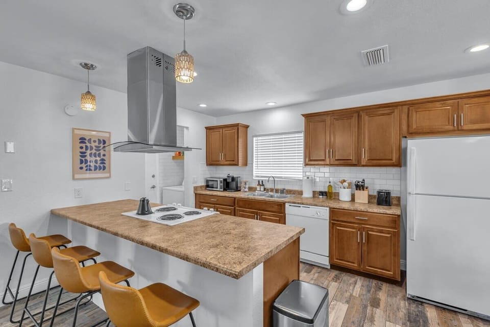 Whole view of the kitchen showcasing kitchen island and refrigerator seamlessly blending with the kitchen walls.