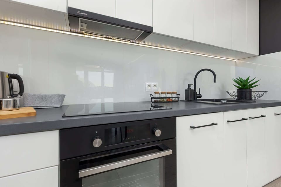 A closer view of the kitchen showcasing the black faucet, countertop, and open shelving for added functionality.
